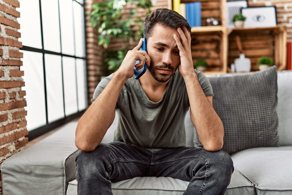 a person sits while holding their head and talking on the phone while thinking about Can drug abuse cause Schizophrenia?