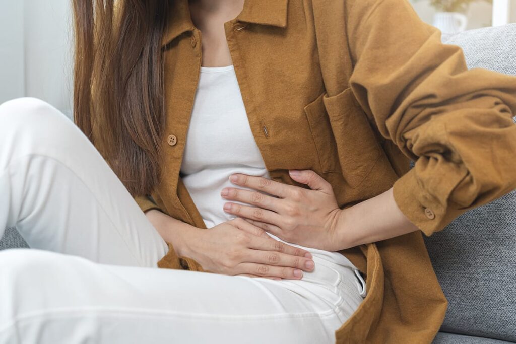a person holds their stomach as they wonder "Does drug abuse cause constipation?"